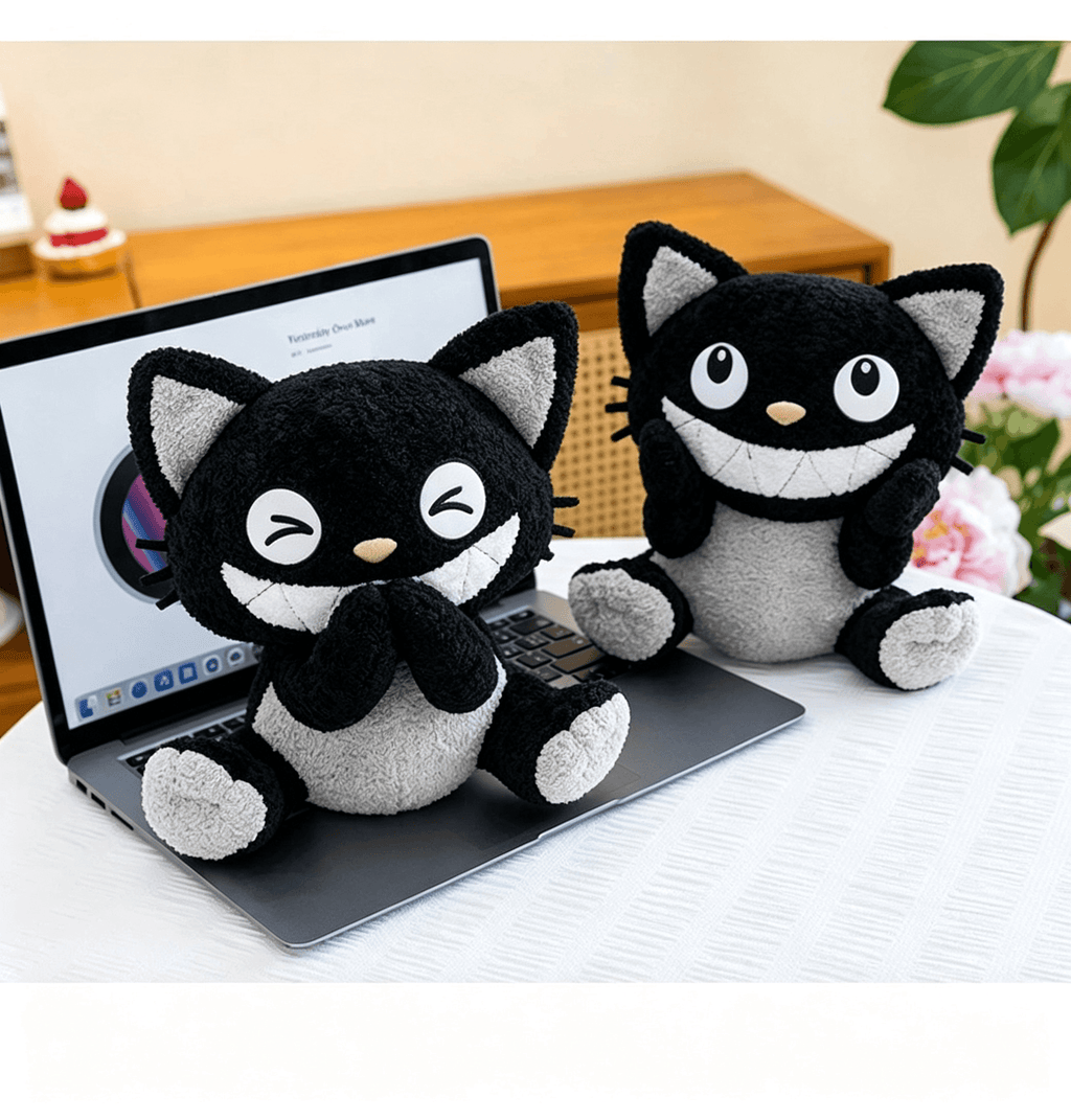 Cute black and white cat plush toys sitting on a laptop on a cozy work desk