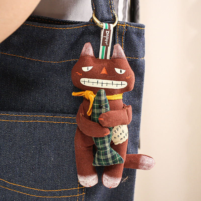 Brown black cat bag charm hanging on a blue denim handbag strap