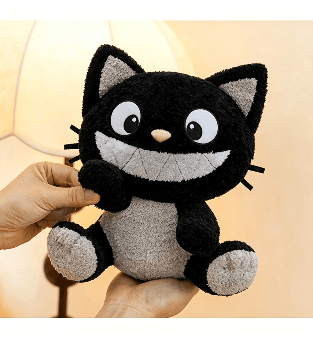 Close-up of a cute black and white cat plush toy being held by hands with a smiling expression
