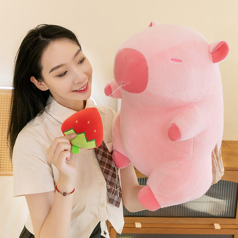 Model showing detachable strawberry fruit accessory of pink capybara plush, versatile kawaii capybara stuffed animal toy