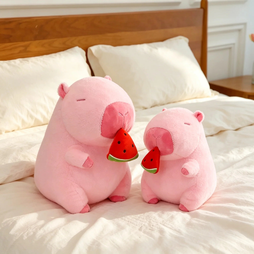Two sizes pink capybara plush holding watermelon slice on bed, size comparison kawaii capybara stuffed animal plush toy